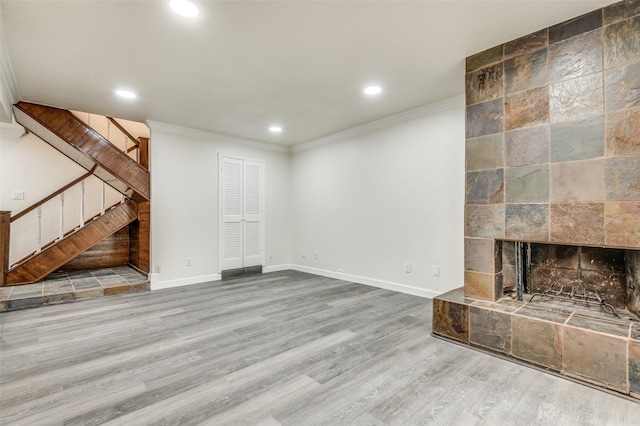 unfurnished living room featuring wood-type flooring, a fireplace, and crown molding