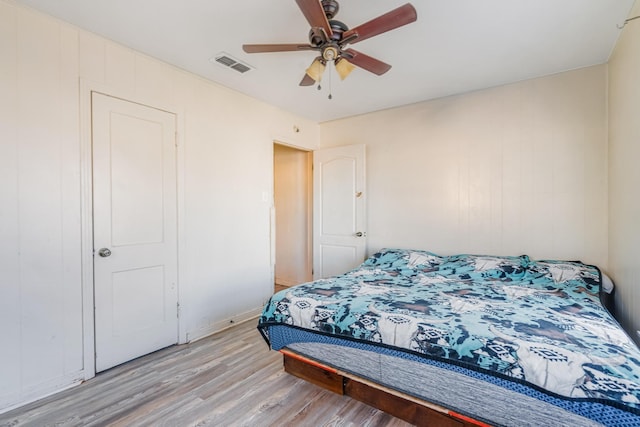 bedroom with light wood-style floors, ceiling fan, and visible vents