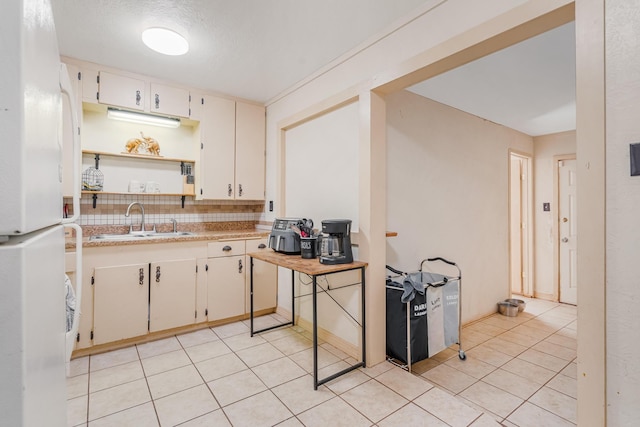 kitchen featuring a sink, white cabinetry, light countertops, freestanding refrigerator, and open shelves