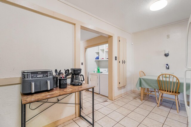 interior space with a textured ceiling, washing machine and clothes dryer, and light tile patterned flooring