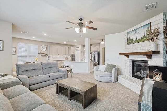 living room with light carpet, a fireplace, and ceiling fan