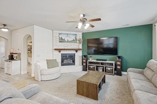 living room with ceiling fan and a fireplace