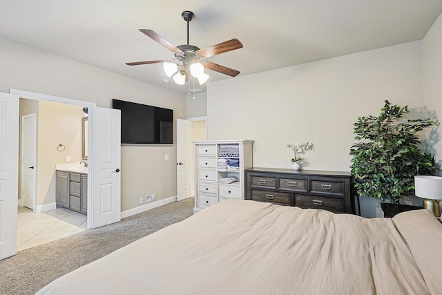 bedroom featuring ceiling fan, light colored carpet, and ensuite bath