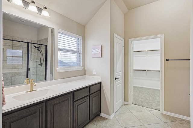 bathroom with a shower with door, vanity, lofted ceiling, and tile patterned floors