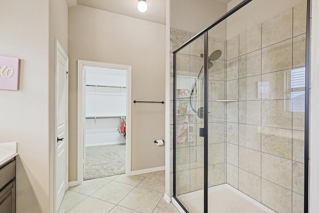 bathroom with a shower with door, vanity, and tile patterned floors