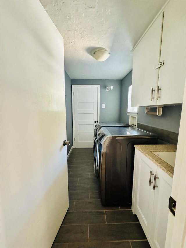 laundry room featuring a textured ceiling, cabinets, and washing machine and clothes dryer