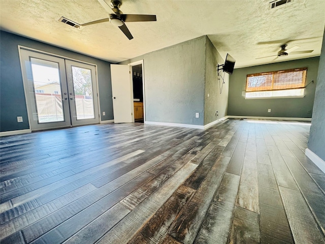 empty room with ceiling fan, dark wood-type flooring, french doors, and a textured ceiling