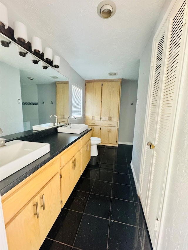 bathroom featuring vanity, a textured ceiling, tile patterned floors, and toilet