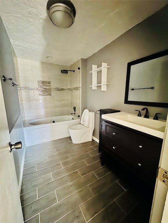 full bathroom with tiled shower / bath, vanity, and toilet