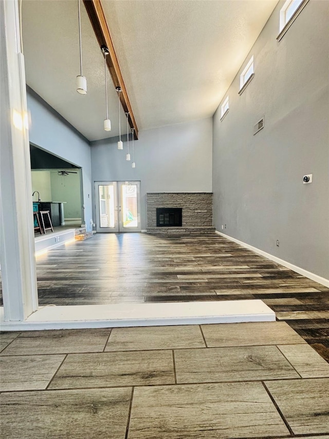 unfurnished living room featuring a stone fireplace, dark hardwood / wood-style flooring, and french doors