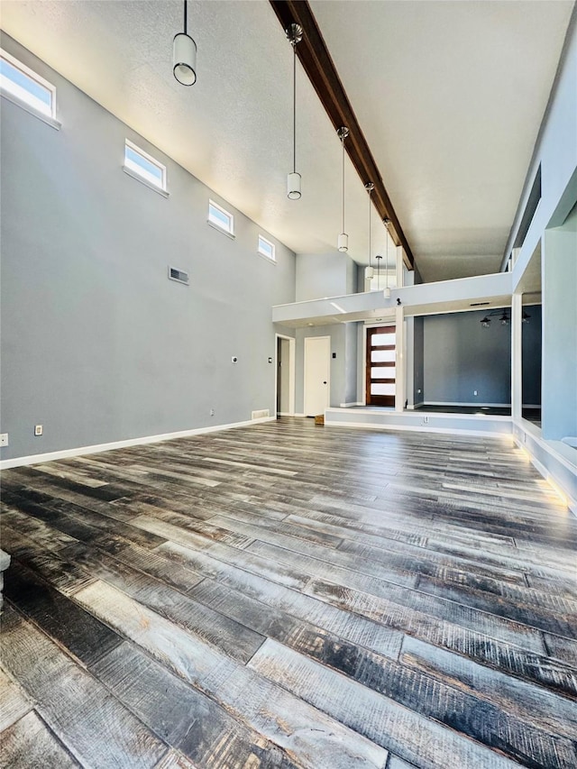 unfurnished living room with wood-type flooring and a towering ceiling