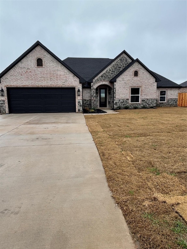 french country inspired facade with a garage and a front lawn