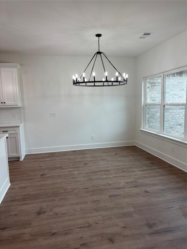 unfurnished dining area with dark wood-type flooring and a chandelier