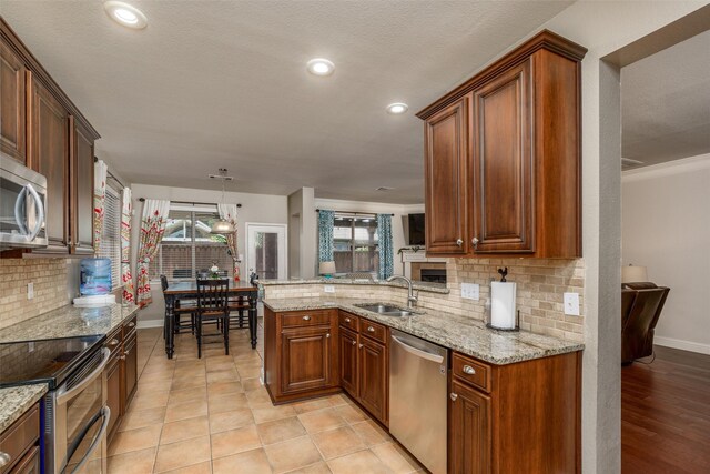 kitchen with stainless steel appliances, light stone countertops, decorative backsplash, and light tile patterned floors