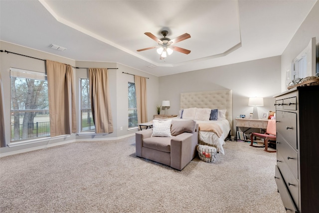 bedroom featuring ceiling fan, a tray ceiling, and carpet