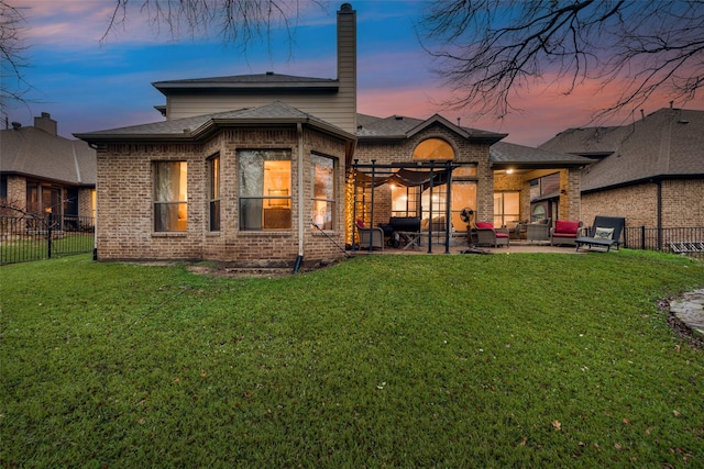 back house at dusk featuring a yard, an outdoor living space, and a patio area