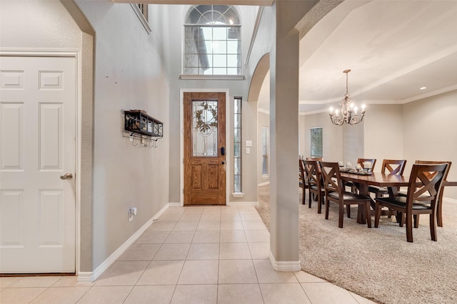 tiled entryway featuring crown molding and a notable chandelier