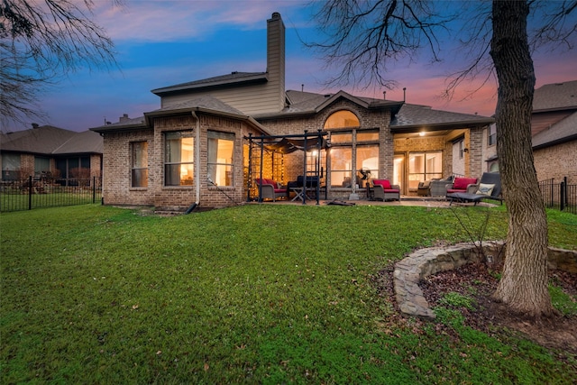 back house at dusk with a lawn, outdoor lounge area, and a patio