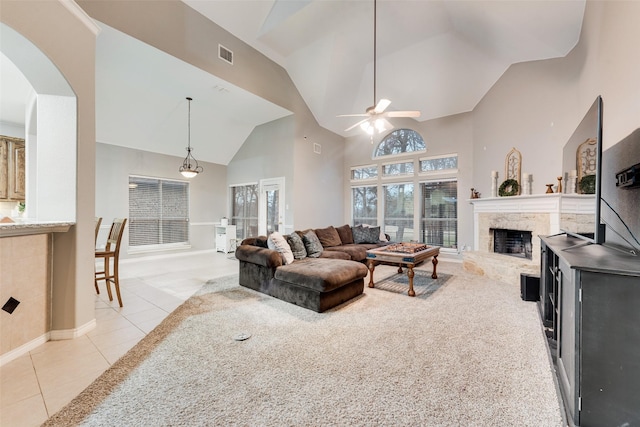 tiled living room with ceiling fan, a high end fireplace, and high vaulted ceiling