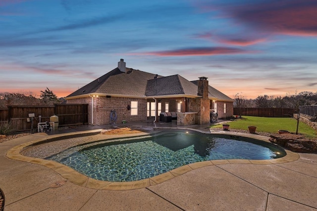 pool at dusk featuring a patio and a yard