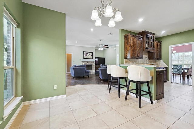 kitchen with dark brown cabinetry, a peninsula, a breakfast bar, light countertops, and glass insert cabinets