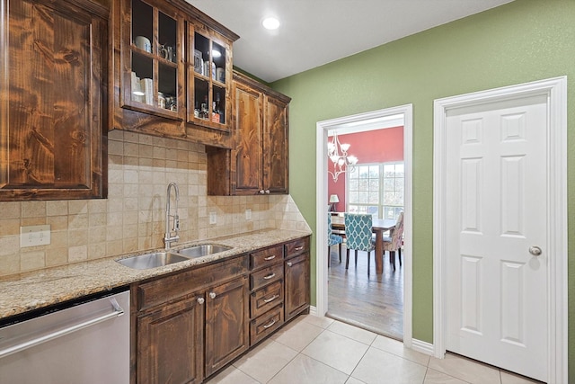 kitchen featuring light stone counters, sink, light tile patterned floors, and stainless steel dishwasher