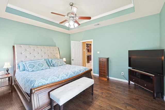 bedroom with crown molding, a tray ceiling, and dark wood-type flooring