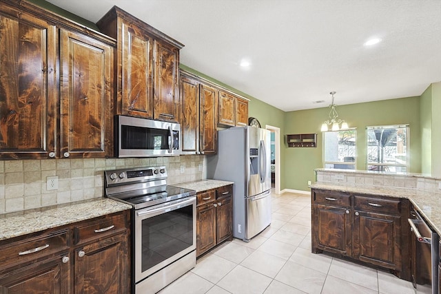 kitchen with light tile patterned flooring, dark brown cabinetry, hanging light fixtures, stainless steel appliances, and decorative backsplash