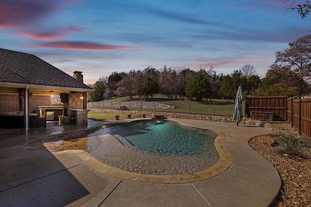 pool at dusk with ceiling fan, a patio, and an outdoor stone fireplace