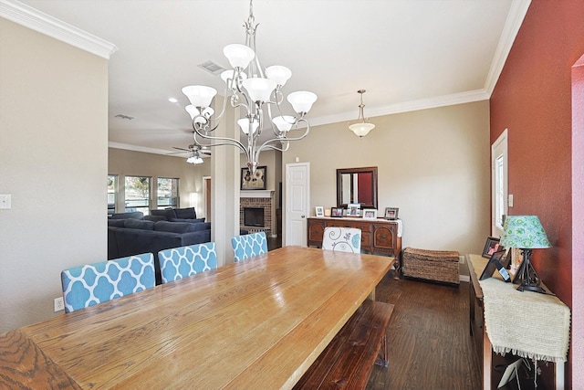 dining space featuring ceiling fan with notable chandelier, a fireplace, ornamental molding, and dark hardwood / wood-style floors