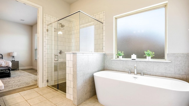 bathroom with tile patterned flooring, shower with separate bathtub, and tile walls