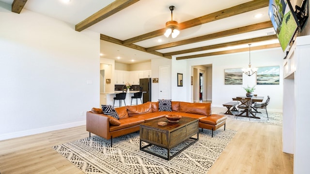 living room featuring beam ceiling, ceiling fan with notable chandelier, and light hardwood / wood-style flooring