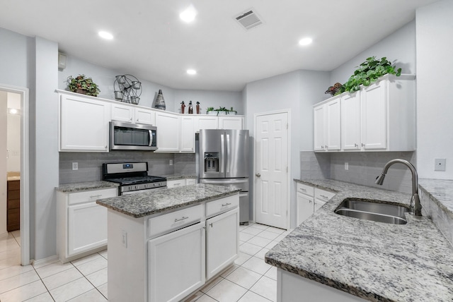 kitchen featuring a kitchen island, white cabinetry, sink, stainless steel appliances, and light stone countertops