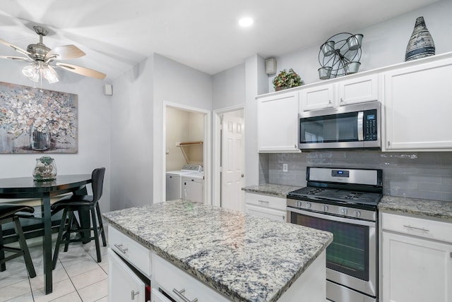 kitchen featuring decorative backsplash, stainless steel appliances, washer and dryer, and white cabinets