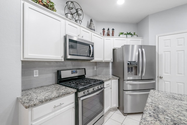 kitchen featuring white cabinetry, appliances with stainless steel finishes, light stone counters, and backsplash