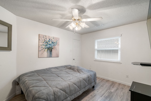 bedroom with ceiling fan, a textured ceiling, and light hardwood / wood-style flooring