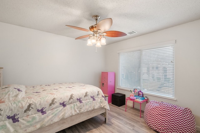 bedroom featuring ceiling fan, light hardwood / wood-style flooring, and a textured ceiling