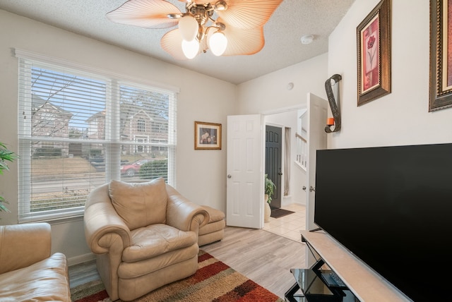 sitting room with ceiling fan, a textured ceiling, a healthy amount of sunlight, and light wood-type flooring