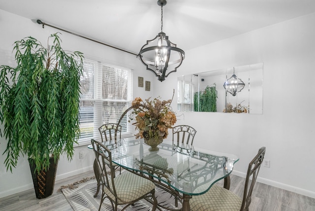 dining area with an inviting chandelier, wood-type flooring, and a healthy amount of sunlight