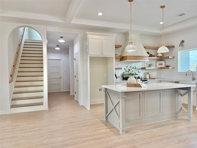 kitchen with white cabinetry, decorative light fixtures, light hardwood / wood-style floors, and a kitchen island