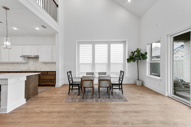 dining room featuring high vaulted ceiling, light hardwood / wood-style flooring, and a wealth of natural light