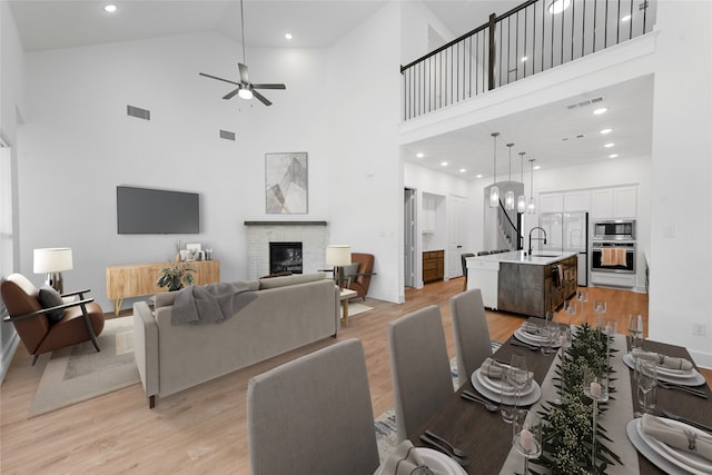 living room with a brick fireplace, sink, and light wood-type flooring