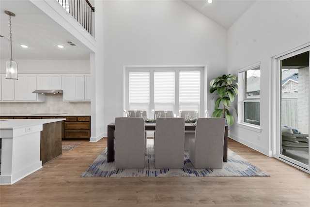 dining area featuring high vaulted ceiling and light hardwood / wood-style floors