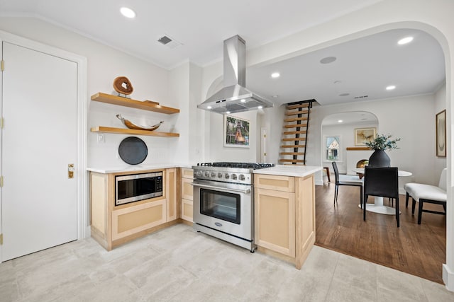 kitchen with island range hood, light brown cabinetry, arched walkways, stainless steel appliances, and a peninsula