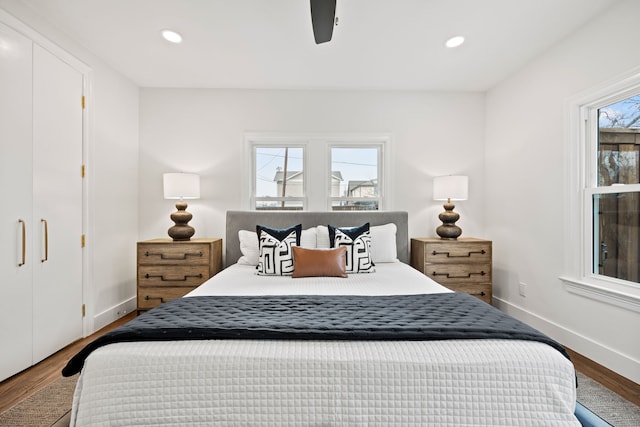 bedroom with baseboards, wood finished floors, recessed lighting, and multiple windows