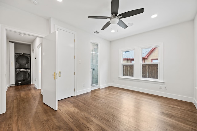 interior space with stacked washer / drying machine, wood finished floors, visible vents, baseboards, and ceiling fan