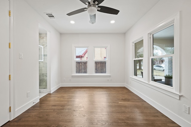empty room with visible vents, baseboards, dark wood-style floors, and a wealth of natural light