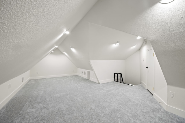 bonus room featuring vaulted ceiling, a textured ceiling, and carpet flooring