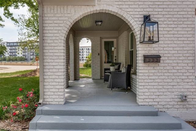 view of exterior entry with brick siding and a porch