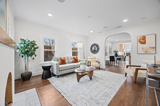 living room with arched walkways, wood finished floors, visible vents, and recessed lighting